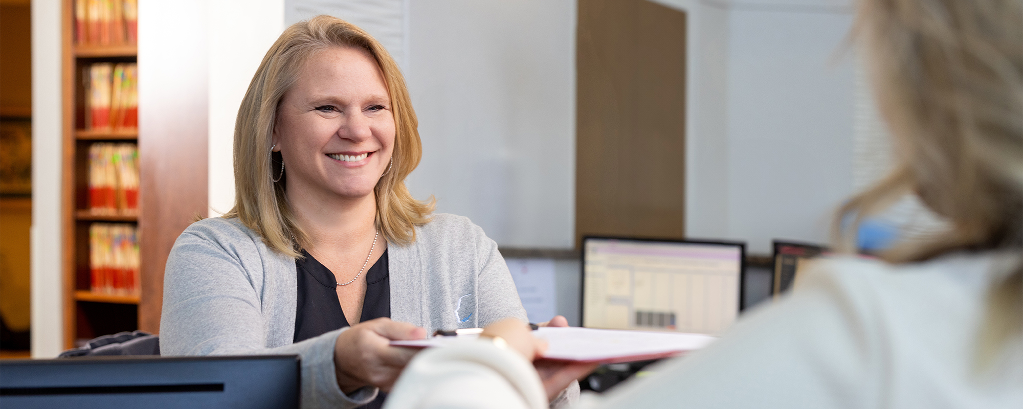 Front desk person handing a patient paperwork.